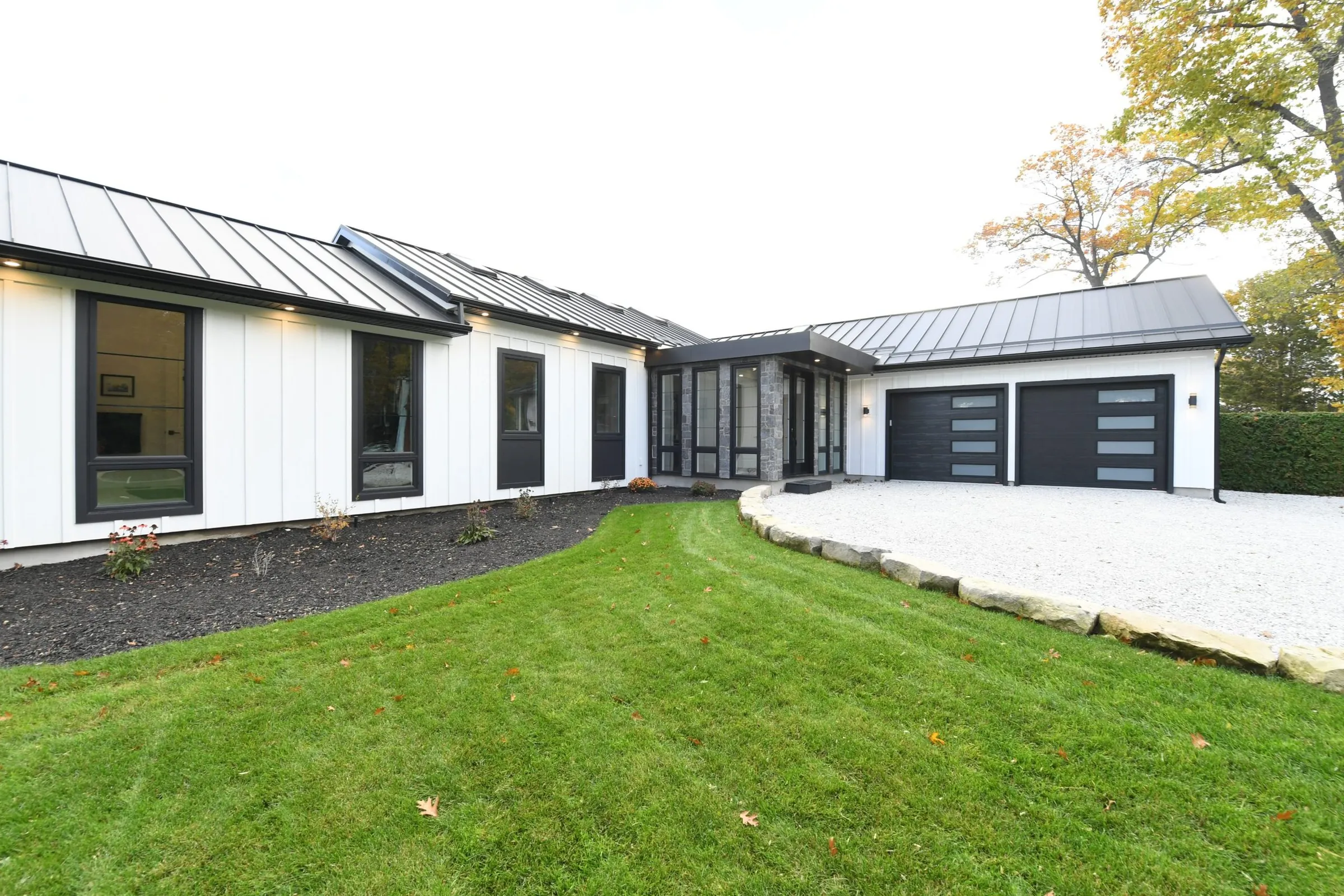 White board and batten home with a black roof